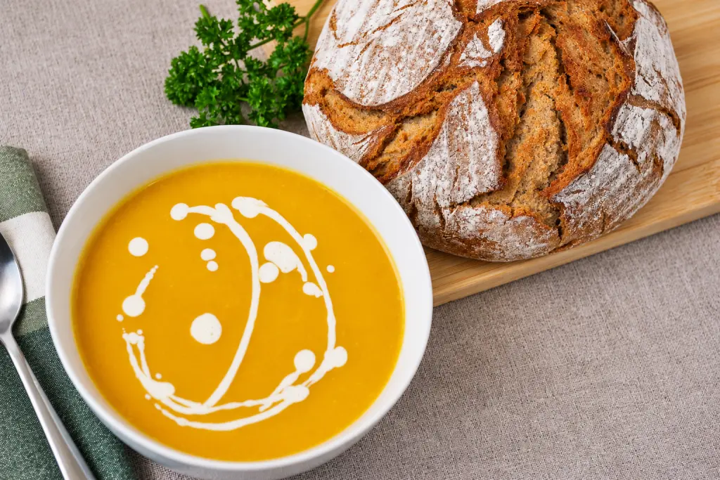 Creamy pumpkin soup with rustic bread and fresh parsley