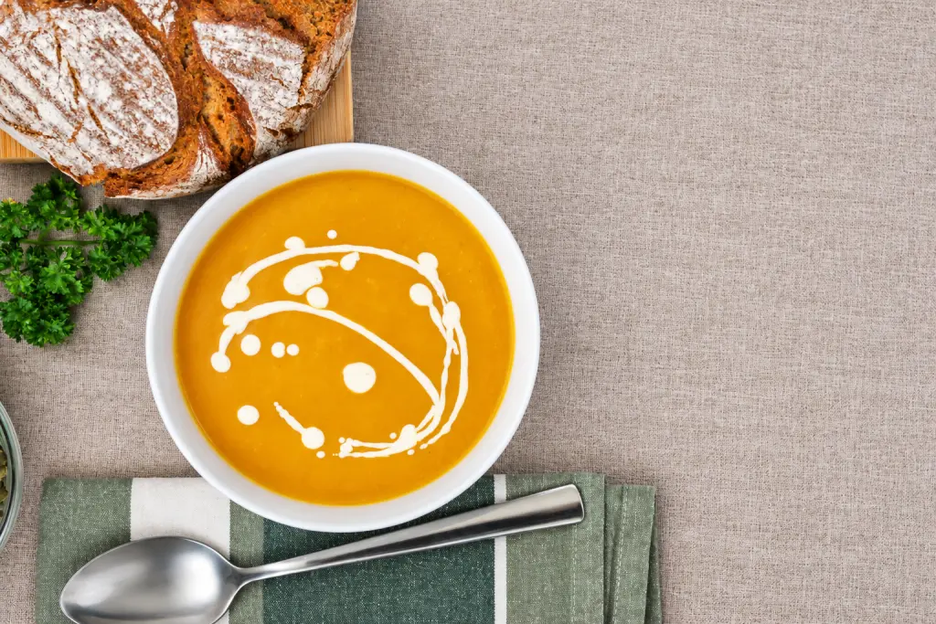 Creamy pumpkin soup with a vegan sour cream swirl and rustic bread